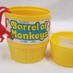 Two red monkeys hanging out of a yellow barrel that holds all the money pieces.