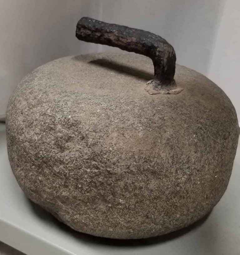 An old curling stone with a curved metal handle