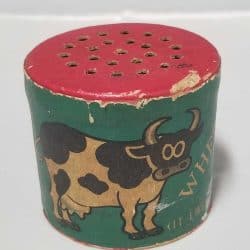 Green tube with a red top with holes. There's a cow drawing on the front.