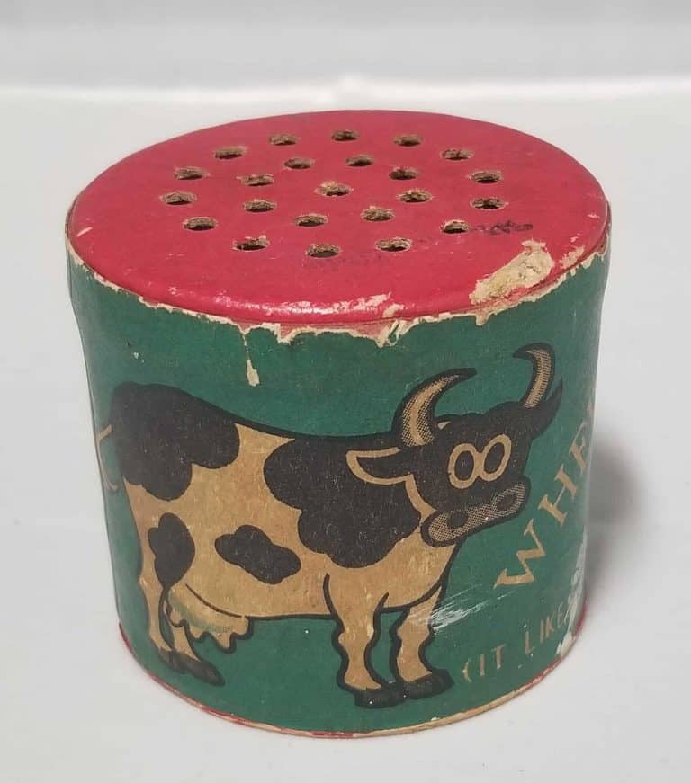 Green tube with a red top with holes. There's a cow drawing on the front.