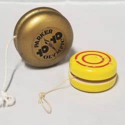 Two yo-yos. One gold coloured with Parker Yo Yo Olympic written on it. The other is yellow with 2 red circles painted on the side.