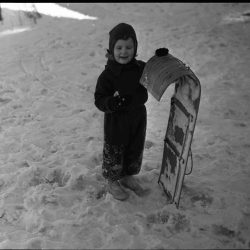 young boy with a toboggan slightly smaller than him