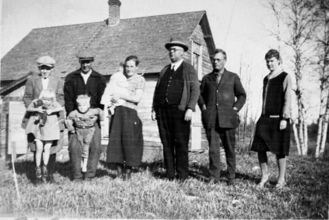 Adults and children lined up outside a homestead