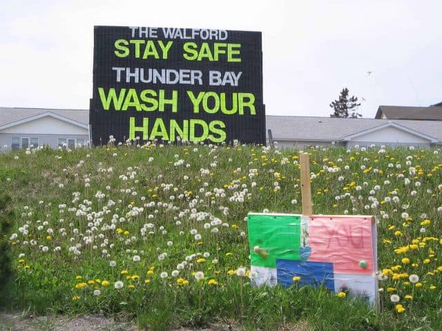 Sign on a hill saying The Walford - Stay Safe Thunder Bay. Wash your hands.