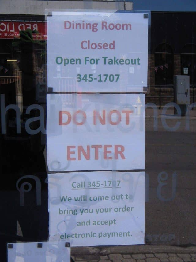 Signs on a business saying Dining Room Closed, Open for Takeout. Do not enter. We will come out to bring you your order and accept electronic payment