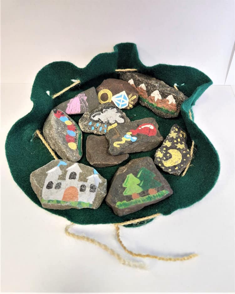 Bunch of rocks with castles, trees, star and moons and other designs painted on them.