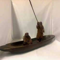 hand-carved wooden boat with 2 men in it.