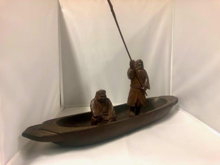 hand-carved wooden boat with 2 men in it.