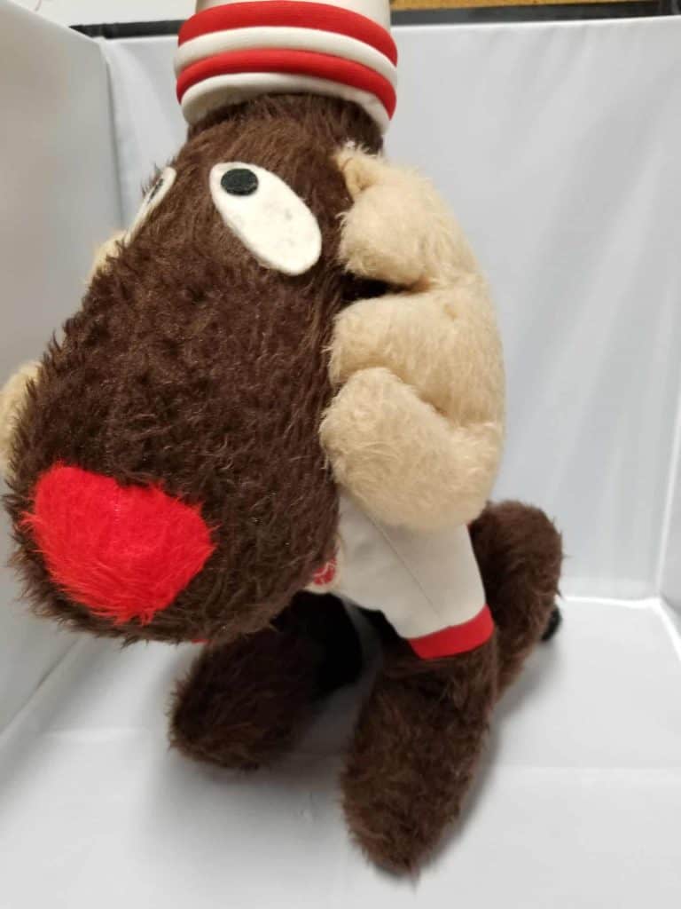 Stuffed Moose with a striped white and red hat wearing a white sweater with red cuffs.