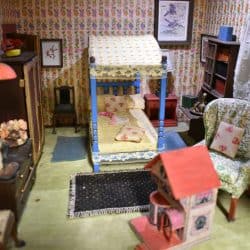 Girls bedroom showing the canopy bed and a doll house on the floor.