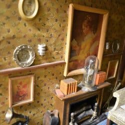 Various items on a wall including a plate, painting, and some books on a fireplace mantle.