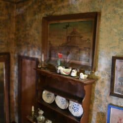 Cabinet with plates display on it and a painting above.