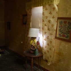 Lamp in front of a window with yellow curtains.