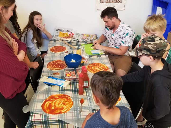Kids around a table making homemade pizzas.