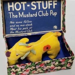 Yellow dog in a blue box with the words: Hot-Stuff The Mustard Club Pup. He's some fellow and no mis-steak. Meat his pals at the Mustard Club.