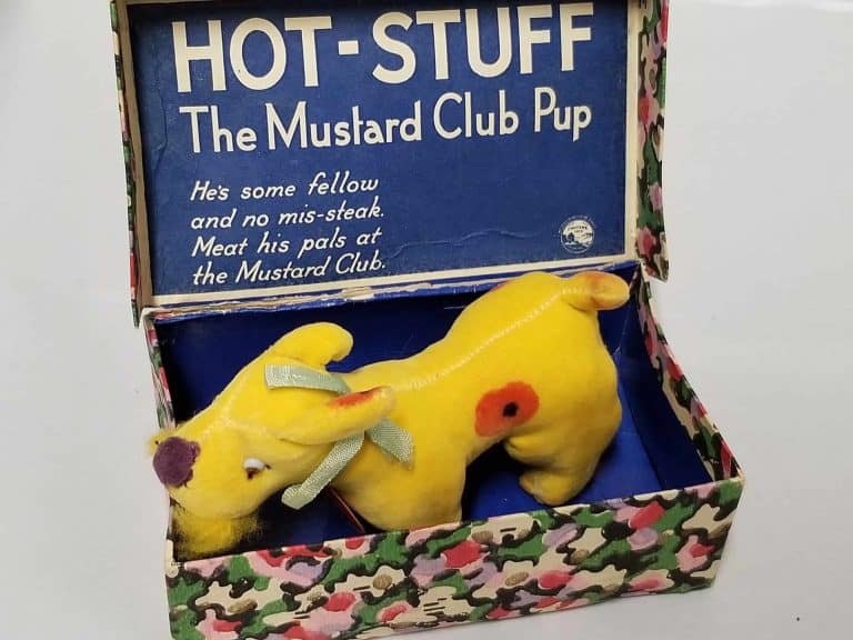 Yellow dog in a blue box with the words: Hot-Stuff The Mustard Club Pup. He's some fellow and no mis-steak. Meat his pals at the Mustard Club.