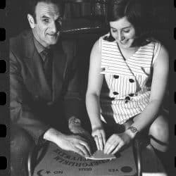 Black and white photo of two people using an ouija board