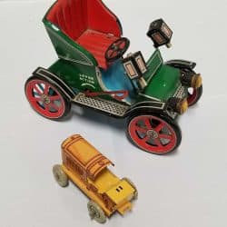 Green Roadster-type automobile and a small yellow and orange tin tractor.