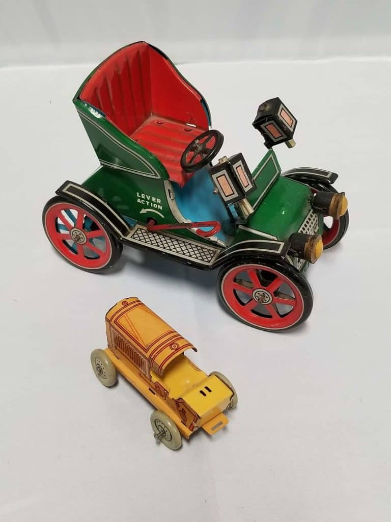 Green Roadster-type automobile and a small yellow and orange tin tractor.