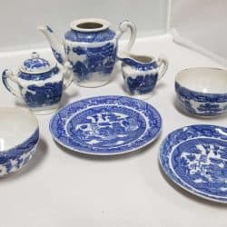 White plates with blue Japanese images depicted on them. Set includes 2 plates, 2 cups, teapot, sugar bowl, and creamer.