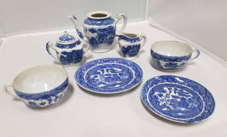 White plates with blue Japanese images depicted on them. Set includes 2 plates, 2 cups, teapot, sugar bowl, and creamer.