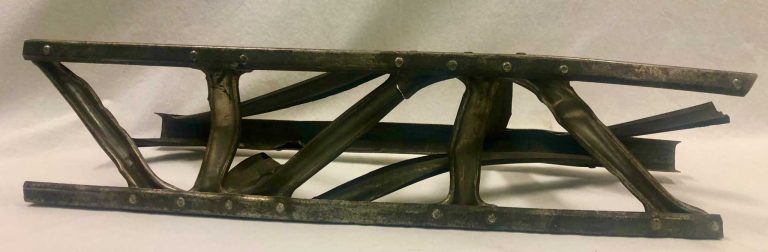 Aluminum frame with three pieces of metal held together by bolts.